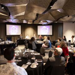 Audience watch the four panel speakers at UQ's research and innovation week